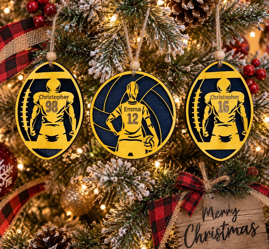 Three yellow and navy personalized sports ornaments hanging on a decorated Christmas tree.